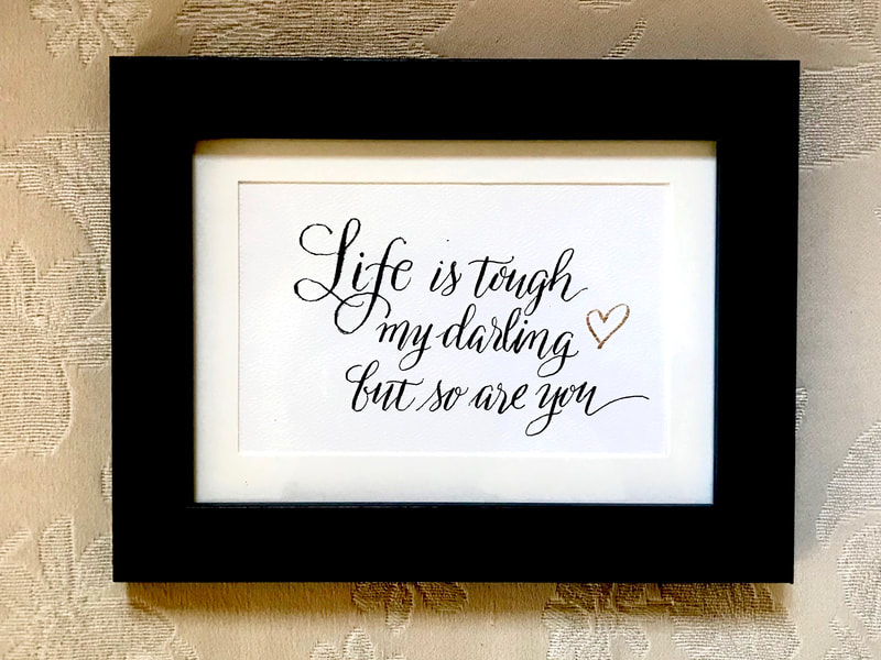 Hand Lettered Calligraphy Quote in black and gold ink "Life is tough my darling but so are you"